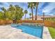 Beautiful backyard showcasing a pristine pool, lush landscaping, and tall palm trees at 1448 Canyon Ledge Ct, Las Vegas, NV 89117