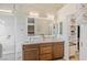 Bathroom featuring wood cabinets, double sinks, a large mirror, and a walk-in shower with glass doors at 1845 Candle Bright Dr, Henderson, NV 89074