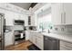 Bright kitchen boasts white cabinets, quartz countertops, stainless steel appliances, and a farmhouse sink at 211 Kokopelli Ct, Henderson, NV 89074
