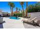 Serene backyard oasis featuring a beautiful pool, lounge chairs, and mature palm trees at 211 Kokopelli Ct, Henderson, NV 89074