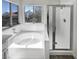 Bright bathroom featuring a soaking tub and a separate glass-enclosed shower near large windows at 2306 Jared Ct, North Las Vegas, NV 89032