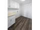 Well-lit laundry room featuring stylish wood-look flooring, bright white cabinets, and a practical beige countertop at 2306 Jared Ct, North Las Vegas, NV 89032