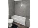 Bathroom with a bathtub and shower, featuring a granite look tile and standard fixtures at 2606 S Durango Dr # 214, Las Vegas, NV 89117