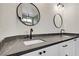 Modern bathroom vanity with double sinks, dark quartz countertop, and two decorative mirrors at 305 Napa Hills Dr, Las Vegas, NV 89144