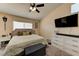 This comfortable bedroom includes a TV, plenty of storage, natural light, and a dark gray ottoman at 3823 Aspen Creek Ave, North Las Vegas, NV 89031