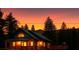 Charming cabin-style home with a green metal roof and a wraparound deck against a fiery sunset backdrop at 4178 Matterhorn Way, Las Vegas, NV 89124
