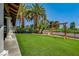 Lush backyard with manicured lawn, mature palm trees, and a pergola for outdoor enjoyment at 5237 Crooked Sky Cir, Las Vegas, NV 89149