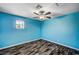 Blue bedroom offers wood-look floors, a ceiling fan, and a window at 5237 Crooked Sky Cir, Las Vegas, NV 89149