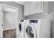 Modern laundry room featuring white front-load washer and dryer, with overhead cabinets at 5237 Crooked Sky Cir, Las Vegas, NV 89149