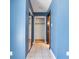 Hallway with blue walls, white tiled floor, closet with sliding mirrored doors and a wood frame door at 6436 Vinecrest Ave, Las Vegas, NV 89108