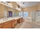 Bright bathroom featuring double sinks, a large mirror, a bathtub, and a glass shower at 7427 Page Ranch Ct, Las Vegas, NV 89131