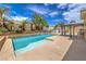 Inviting backyard oasis featuring a sparkling pool, mature palms, and a covered patio at 7427 Page Ranch Ct, Las Vegas, NV 89131