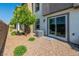 Cozy backyard featuring gravel landscaping, privacy fence, small trees, and a sliding glass door to the house at 7977 Whisper Words Ave, Las Vegas, NV 89113