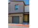 Two-story townhouse featuring a one-car garage, a yellow door, and a simple, modern design at 7977 Whisper Words Ave, Las Vegas, NV 89113