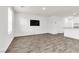 Bright living room with wood-look flooring, a wall-mounted TV, and an open-concept design at 7977 Whisper Words Ave, Las Vegas, NV 89113