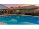 Beautiful sunset view of the backyard swimming pool, patio area, and desert landscape features at 10058 Saint Augustine St, Las Vegas, NV 89183
