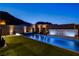 Expansive backyard with a long pool, hot tub, lush lawn, and tranquil seating areas against a mountain view at 10228 Shell Star Ave, Las Vegas, NV 89135
