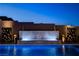 Elegant backyard oasis with a cascading water feature, inviting pool, and artistic privacy screens at dusk at 10228 Shell Star Ave, Las Vegas, NV 89135