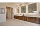 Bright bathroom showcasing a long vanity with double sinks, sleek wood cabinetry, and illuminated mirrors at 10228 Shell Star Ave, Las Vegas, NV 89135