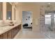 Modern bathroom featuring dual sinks, wood cabinets, and a glass-enclosed shower with marble tiling at 10228 Shell Star Ave, Las Vegas, NV 89135