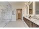 Modern bathroom with marble shower, double vanity, and large, illuminated mirrors at 10228 Shell Star Ave, Las Vegas, NV 89135