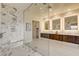Spacious bathroom with a glass shower and marble tiling, with double vanity and illuminated mirrors at 10228 Shell Star Ave, Las Vegas, NV 89135