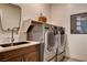 Modern laundry room with stainless steel washer and dryer, sink, and decorative laundry care sign at 10228 Shell Star Ave, Las Vegas, NV 89135