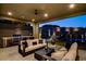 Luxurious outdoor living space with a full kitchen, comfortable seating, and a tranquil pool view at twilight at 10228 Shell Star Ave, Las Vegas, NV 89135