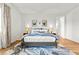Bright main bedroom showcasing a stylish bed, modern decor, and hardwood floors with ensuite access at 10906 Mila Landing Ave, Las Vegas, NV 89166