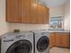 Laundry room with dual front load washer and dryer, ample cabinet space, and a window for natural light at 1105 Malachite Ct, Henderson, NV 89011