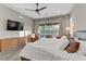 This main bedroom features a ceiling fan, gray wood floors, a large bed, and a sliding glass door to the outside at 15 Reflection Bay Dr, Henderson, NV 89011