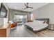 Bright main bedroom features a ceiling fan, gray wood floors, a sliding glass door, and an outdoor seating area at 15 Reflection Bay Dr, Henderson, NV 89011