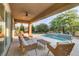 Relaxing covered patio with ceiling fan, wicker chairs, and splash pool with mosaic tile waterfall feature at 15 Reflection Bay Dr, Henderson, NV 89011
