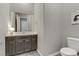 Stylish powder room featuring a modern vanity with gray cabinets, framed mirror, and low-flow toilet at 15 Reflection Bay Dr, Henderson, NV 89011