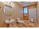 A half bathroom with a pedestal sink, toilet, and a door leading to the backyard at 201 Palmarosa St, Henderson, NV 89015