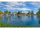 Scenic view of the community pond, highlighted by a waterfall feature, lush greenery, and mature trees at 2713 Tanagrine Dr, North Las Vegas, NV 89084