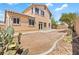 A two-story home showing the backyard with desert landscaping, a small patio, and natural rock accents, ready for your personal touch at 3273 Alcudia Bay Ave, Las Vegas, NV 89141