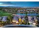 Stunning aerial view of a lakeside property with a golf course and city lights in the background at twilight at 5162 Estasi St, Las Vegas, NV 89135