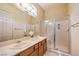 Well-lit bathroom with double sinks, framed mirrors, and glass enclosed shower at 5162 Estasi St, Las Vegas, NV 89135