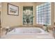 Relaxing soaking tub featuring tiled surround and decorative window at 5162 Estasi St, Las Vegas, NV 89135