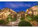 Charming front yard at dusk featuring lush landscaping, a gate and a three-car garage at 5162 Estasi St, Las Vegas, NV 89135