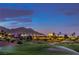 Scenic view of a lush golf course with sprinklers running, set against a mountain backdrop at dusk at 5162 Estasi St, Las Vegas, NV 89135