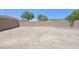 View of expansive tan backyard enclosed by a brick wall with trees and sky above at 5250 Chester Creek Ct, Las Vegas, NV 89141