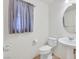 Small powder room with a pedestal sink, round mirror, and a window with gray curtains at 5250 Chester Creek Ct, Las Vegas, NV 89141