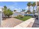 A lush landscaped backyard featuring a brick patio, an artificial lawn, and palm trees at 5990 Ablette Ave, Las Vegas, NV 89122