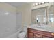 A bathroom featuring a shower and bath combination with a white backsplash, a vanity with dark wood and a mirror at 5990 Ablette Ave, Las Vegas, NV 89122