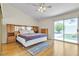 Sunlit primary bedroom with a ceiling fan, light walls, hardwood flooring, and slider to the backyard at 5990 Ablette Ave, Las Vegas, NV 89122