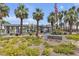 Well-manicured community entrance featuring lush landscaping, palm trees, and signage at 5990 Ablette Ave, Las Vegas, NV 89122