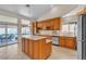 Bright kitchen featuring wood cabinetry, an island, stainless steel appliances, and backyard access at 5990 Ablette Ave, Las Vegas, NV 89122
