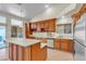 Bright kitchen featuring wood cabinetry, an island, stainless steel appliances, and backyard access at 5990 Ablette Ave, Las Vegas, NV 89122